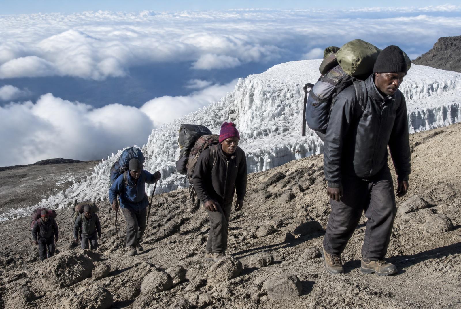 Experienced Tanzanian Kilimanjaro guide and porters on the trail